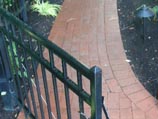 Red clay paver walkway and wrought-iron gate