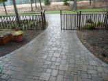 Paver walkway through iron gate with custom garden box
