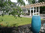Backyard fountain in garden bed with paver patio in the background