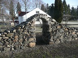 Fitted self-supported rock arch with river stone retaining wall