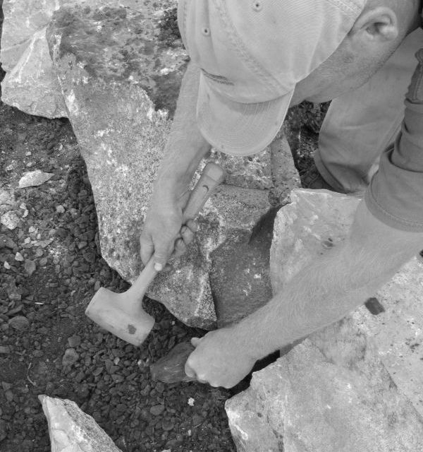 Owner Nate Lynch hammering rock retaining wall into place Owner Nate Lynch hammering rock retaining wall into place